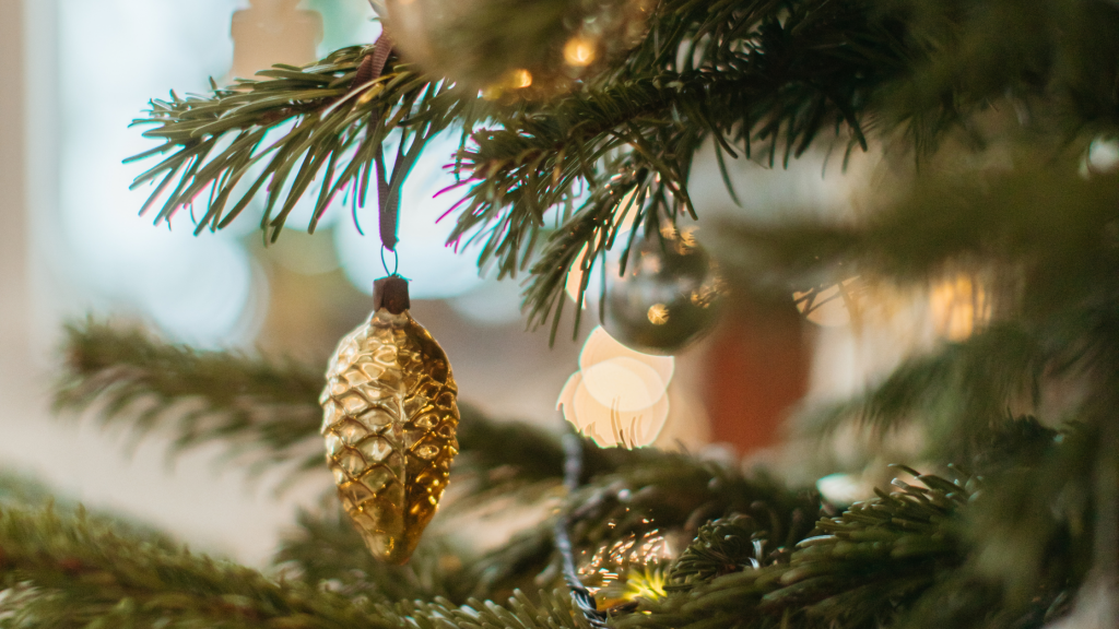 A close up of a gold pine cone ornament on a Christmas tree. Christmas Gift Ideas.